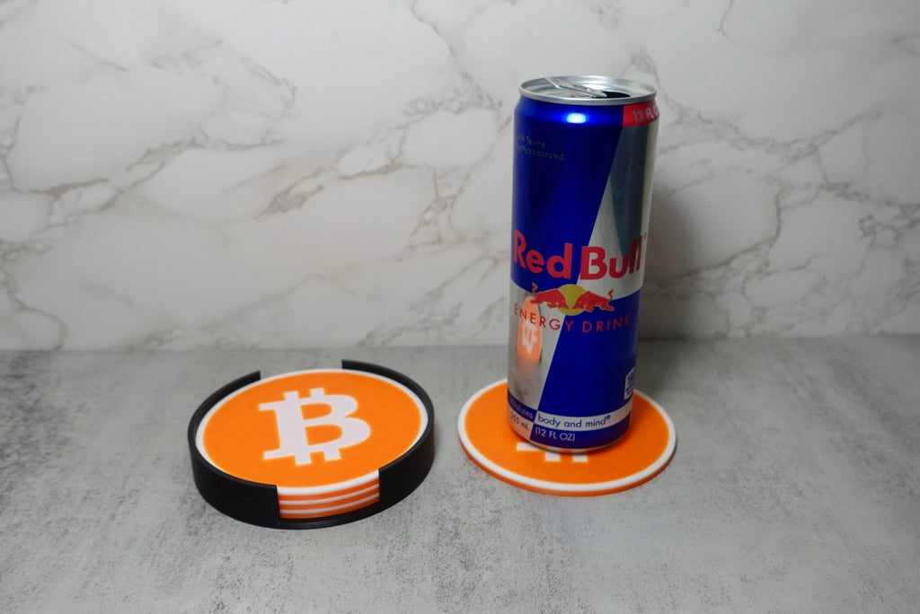 A red bull can and bitcoin coasters on a table.